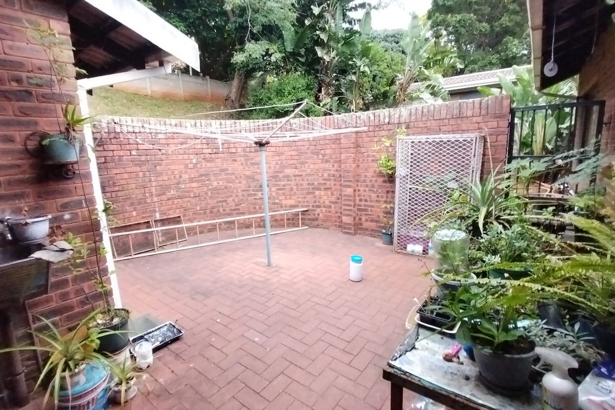 A private rear courtyard featuring brick boundary walls, paved flooring, and a rotary clothesline, offering a functional outdoor utility space.