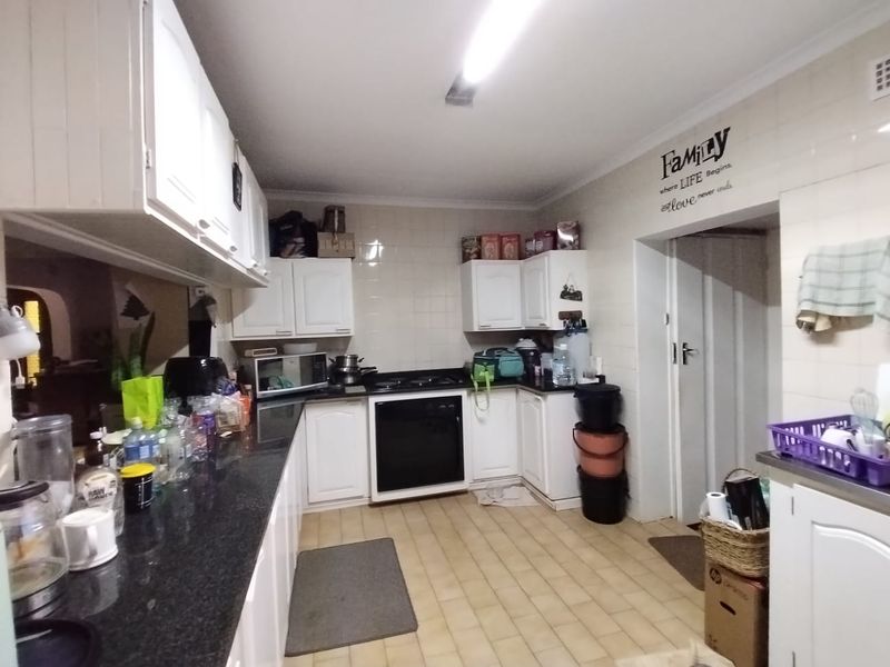 A functional kitchen featuring white built-in cabinetry, dark granite countertops, a built-in oven with gas hob, and tiled flooring.