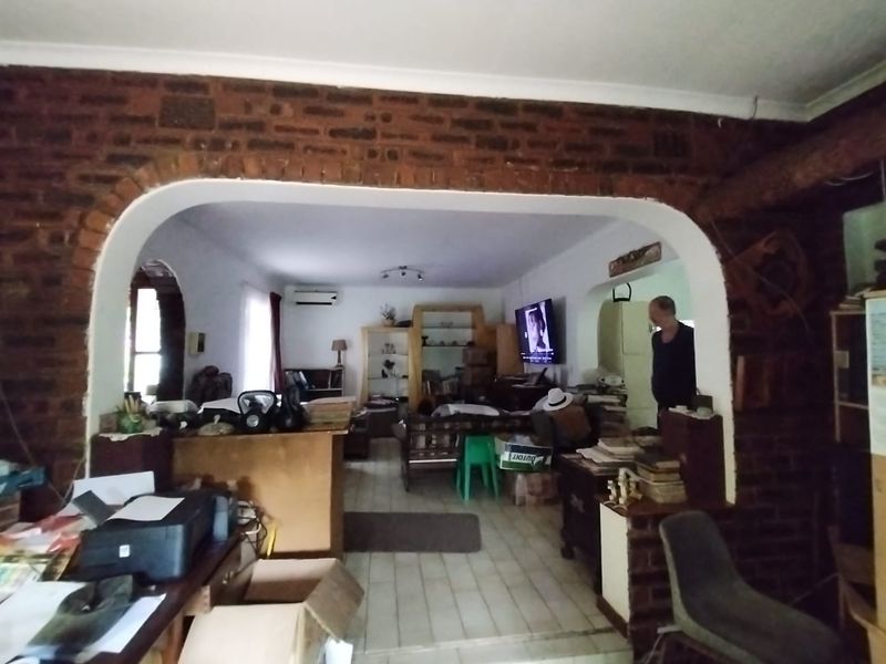 Open plan living area featuring an exposed brick archway, tiled flooring, and a wall-mounted air conditioning unit.