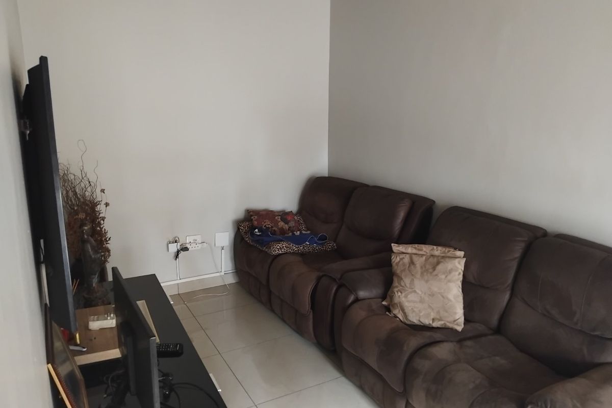 A living room area featuring neutral wall paint and tiled flooring, providing a functional space for relaxation.