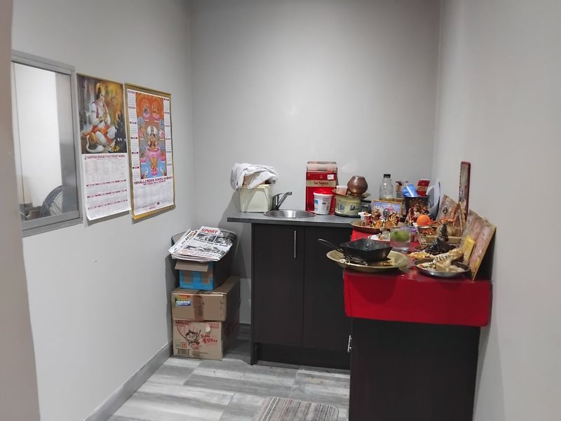 A compact utility or scullery area featuring built-in dark cabinetry, a stainless steel sink, and modern laminate flooring.