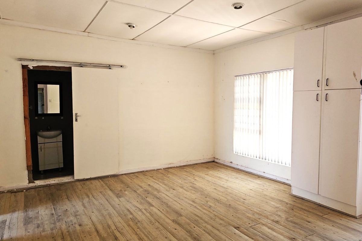 A vacant bedroom featuring wood-look flooring, built-in cabinetry, and an attached en-suite bathroom with a sliding door entry.