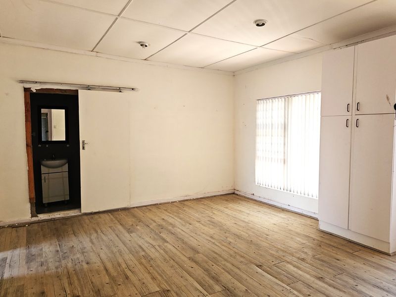 A vacant bedroom featuring wood-look flooring, built-in cabinetry, and an attached en-suite bathroom with a sliding door entry.