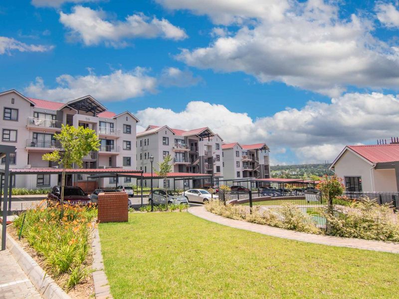 Exterior view of a modern apartment complex featuring multi-story buildings with metal roofs, covered parking carports, and well-maintained landscaped garden areas.