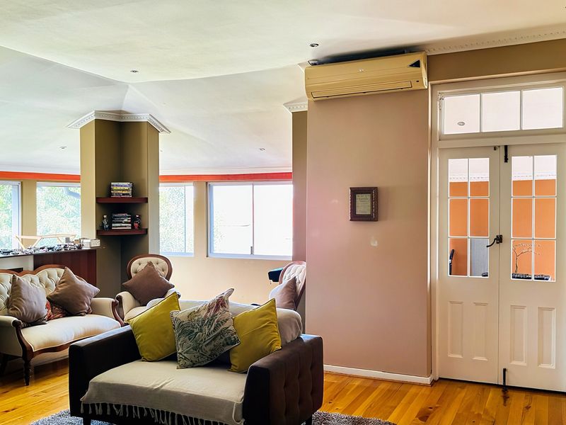 Spacious living area featuring hardwood flooring, recessed lighting, built-in shelving, and classic French doors leading to an adjacent space.