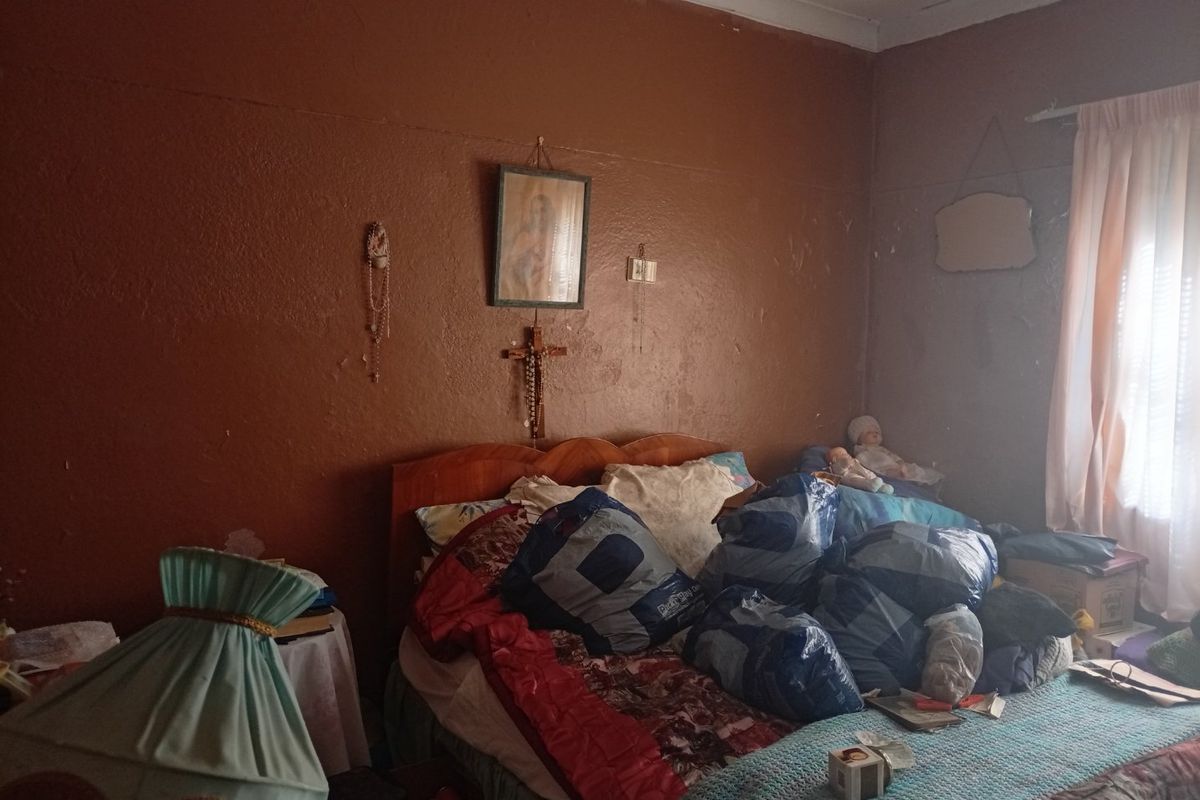 A bedroom featuring dark painted walls with visible surface wear and peeling paint, requiring cosmetic updates to improve the overall condition.