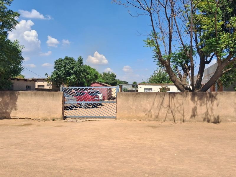 Front view of the property featuring a perimeter wall and a metal driveway gate leading to the yard area.