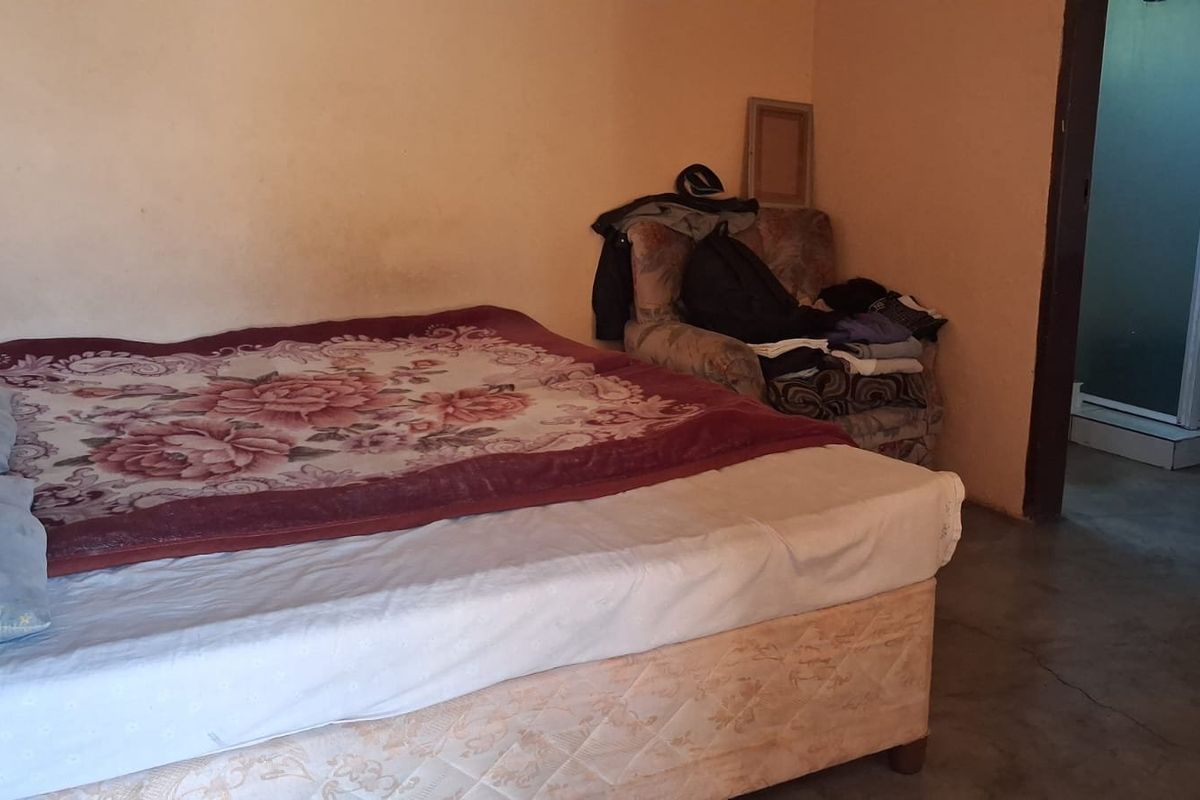 A bedroom featuring plain walls and an adjacent shower cubicle, requiring cosmetic updates to improve the overall condition and appeal of the space.