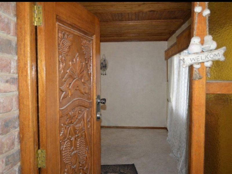 Entrance area featuring a decorative carved timber door, exposed brick accents, and a timber-paneled ceiling, leading into an open interior space.
