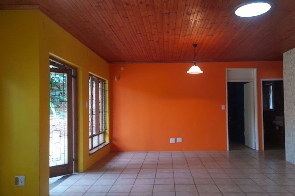 Spacious living area featuring ceramic floor tiles, a warm timber tongue and groove ceiling, and large steel-framed windows providing natural light.