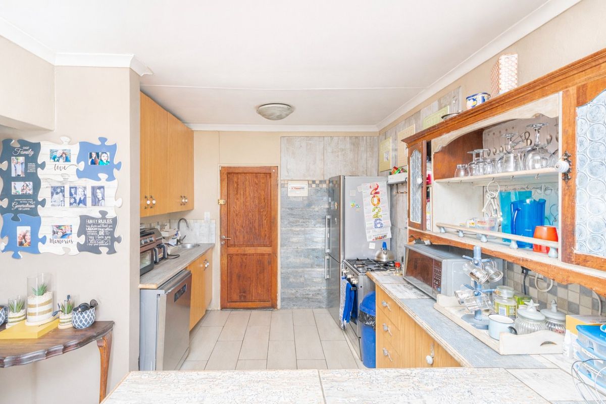 A functional kitchen featuring wooden cabinetry, tiled flooring, and a tiled splashback, offering a practical layout for daily meal preparation.