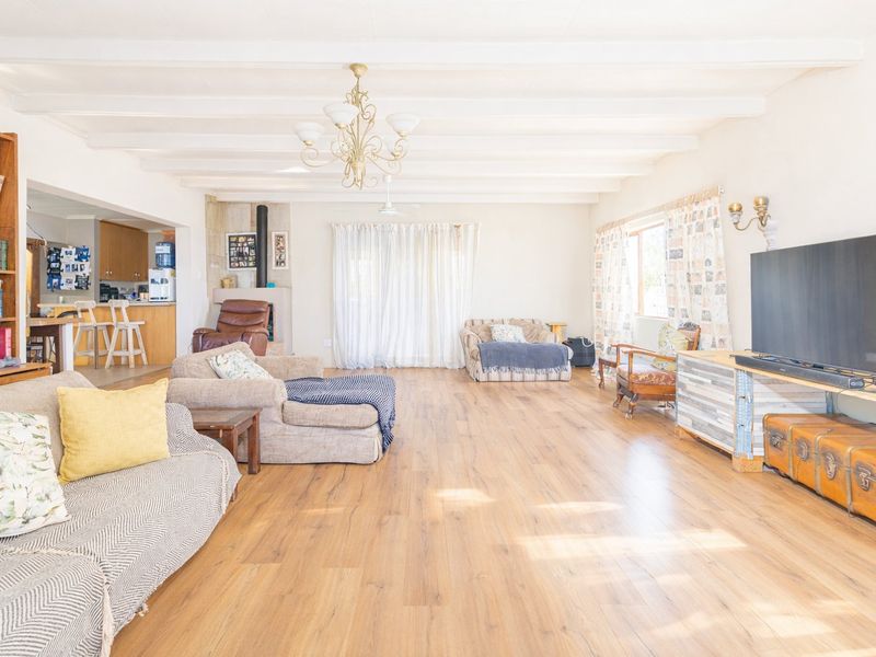Spacious open-plan living area featuring laminate flooring, exposed beam ceilings, and a cozy fireplace, seamlessly connecting to the adjacent kitchen space.