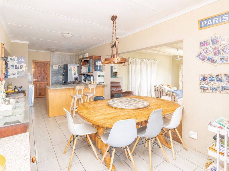 Open-plan kitchen and dining area featuring tiled flooring, a central kitchen island, and pendant lighting, creating a functional and connected living space.