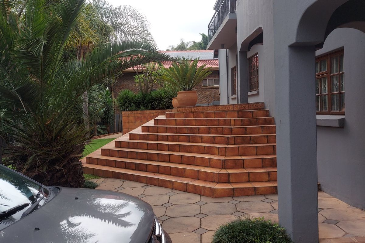 A rear exterior view featuring a tiled staircase leading to a raised patio area, adjacent to the main house structure.