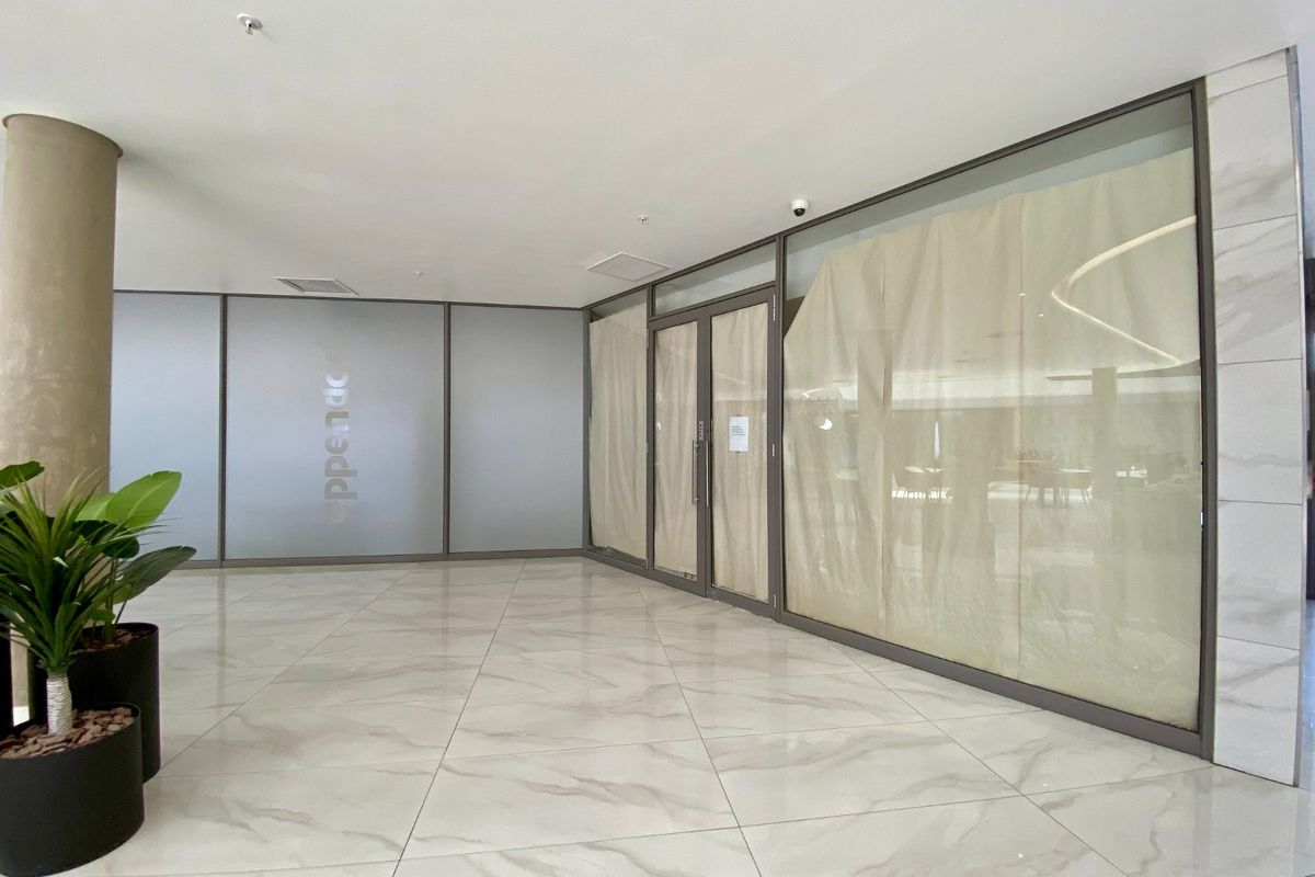 Modern commercial entrance lobby featuring polished marble-look floor tiles, extensive glass partitioning, and a clean, professional aesthetic suitable for a corporate or retail space.