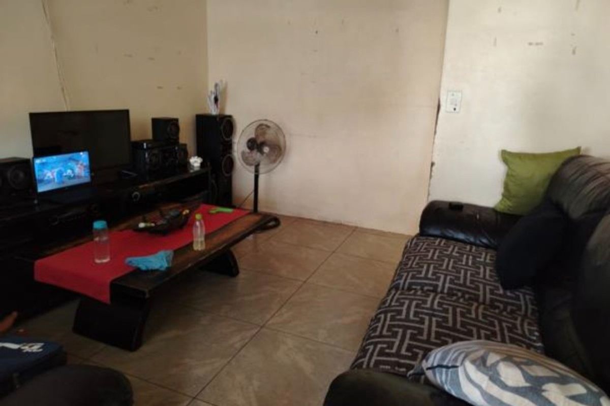 A living room area featuring tiled flooring and plain wall finishes, requiring cosmetic updates to improve the overall aesthetic.