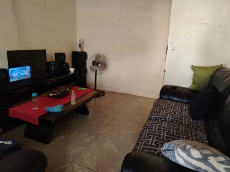A living room area featuring tiled flooring and plain wall finishes, requiring cosmetic updates to improve the overall aesthetic.