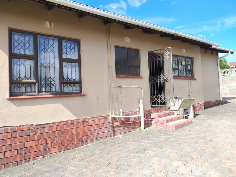Rear exterior view of the house featuring brick paving, security gates, burglar bars, and a functional concrete wash trough.