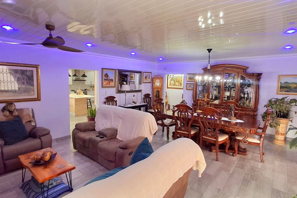 Spacious open-plan living and dining area featuring a glossy panelled ceiling with integrated LED lighting and wood-look tiled flooring.