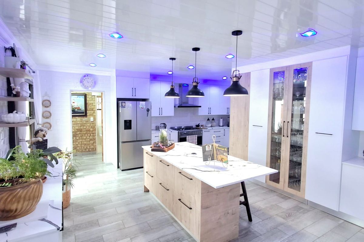 Modern kitchen featuring a central island with stone countertop, integrated cabinetry, built-in oven, extractor fan, and recessed ceiling lighting.