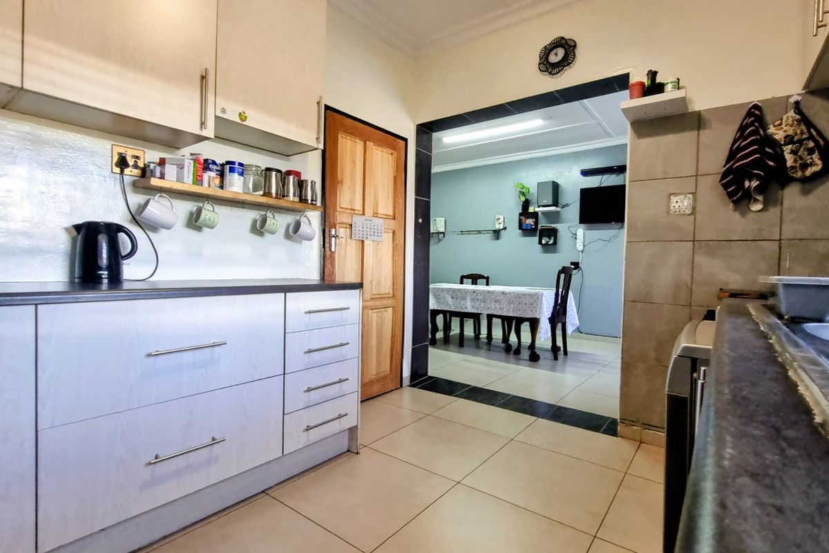 Functional kitchen featuring built-in cabinetry, tiled backsplash, and double sink, with an open transition to the adjacent dining area.