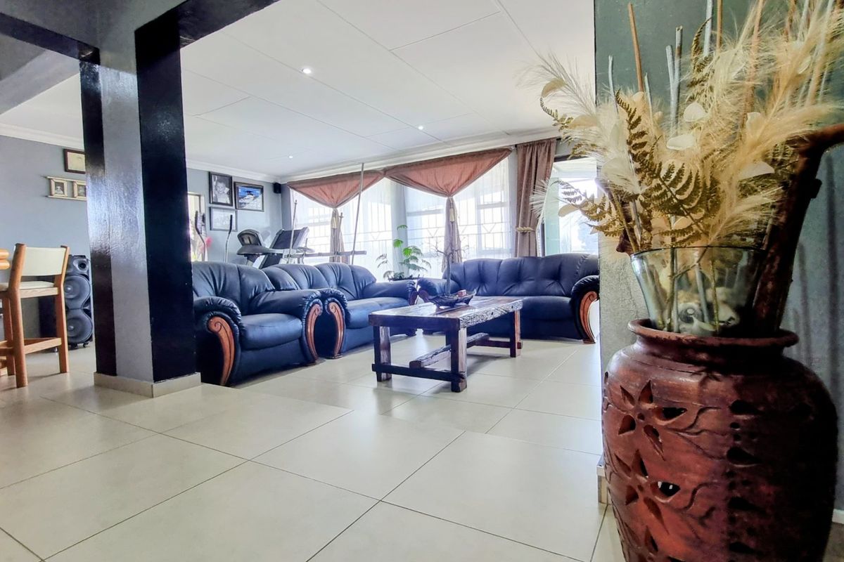 Spacious living room featuring large format floor tiles, recessed ceiling lighting, and an integrated bar area, offering a comfortable and open layout.