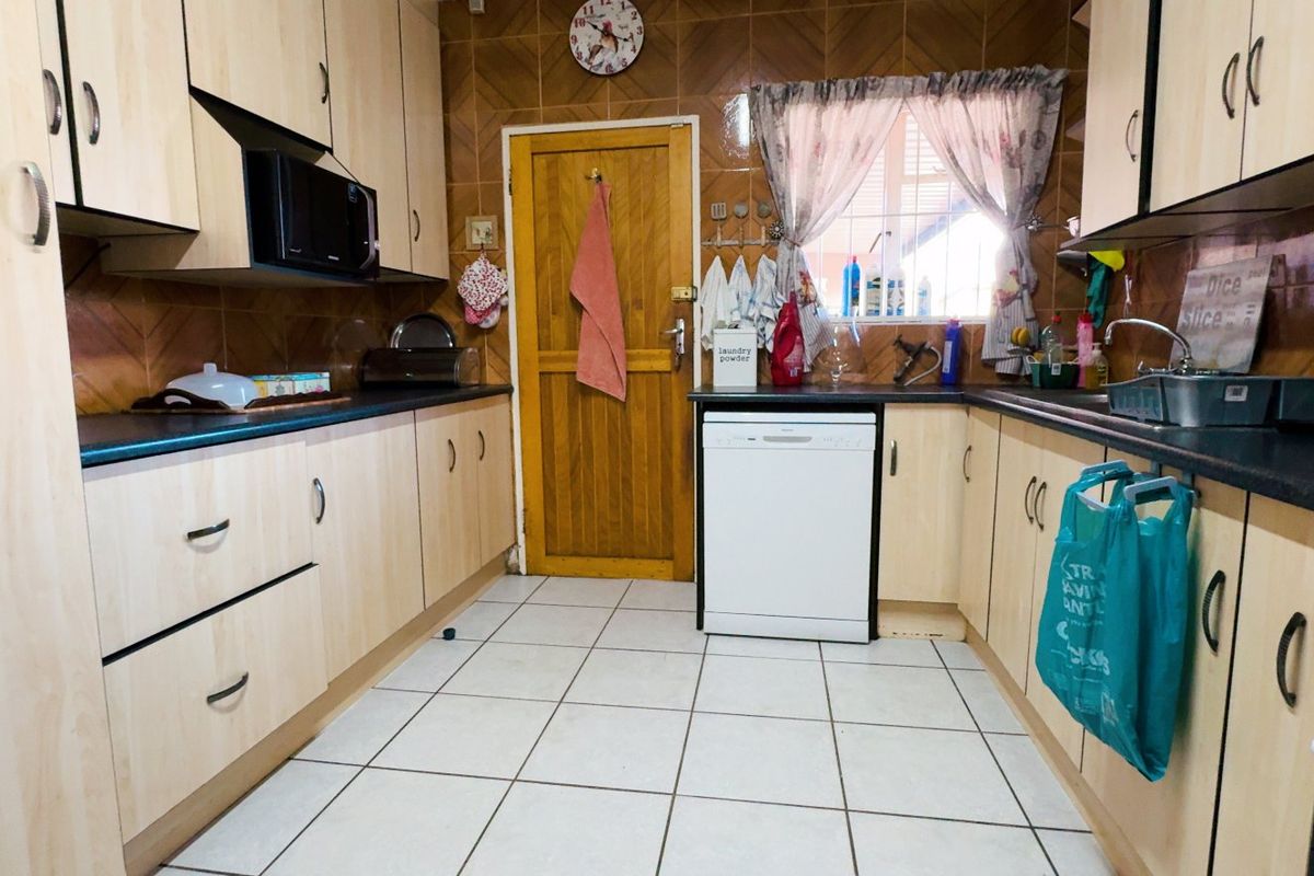 A functional kitchen featuring laminate cabinetry, tiled backsplash, and tiled flooring, equipped with a built-in oven, hob, and dishwasher.