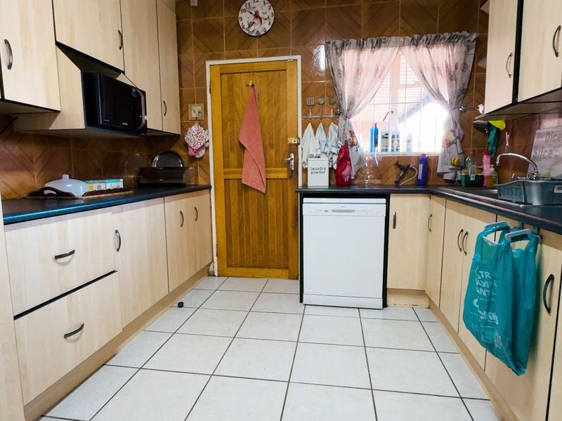 A functional kitchen featuring laminate cabinetry, tiled backsplash, and tiled flooring, equipped with a built-in oven, hob, and dishwasher.