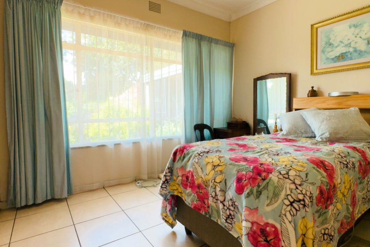 A functional bedroom featuring tiled flooring, built-in cupboards, and large windows that provide natural light.