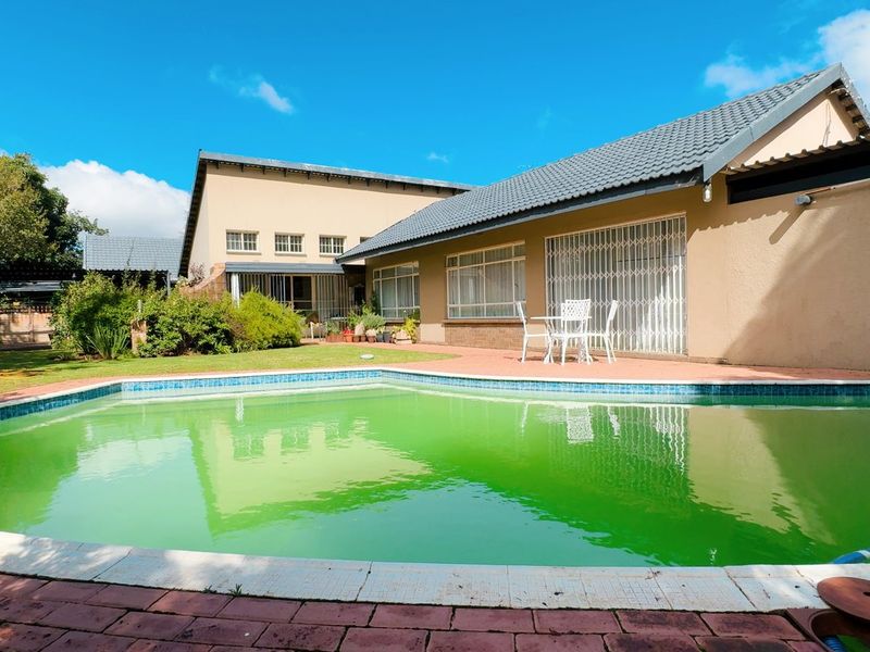 Rear exterior view featuring a swimming pool with paved patio area and access to the main dwelling.