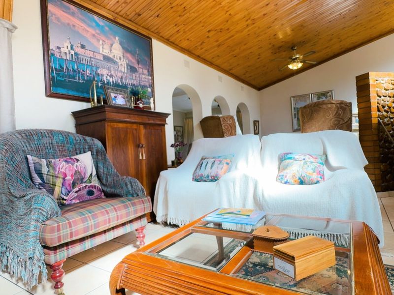 Spacious living room featuring a vaulted timber ceiling, tiled flooring, and an exposed brick feature wall with arched architectural details.