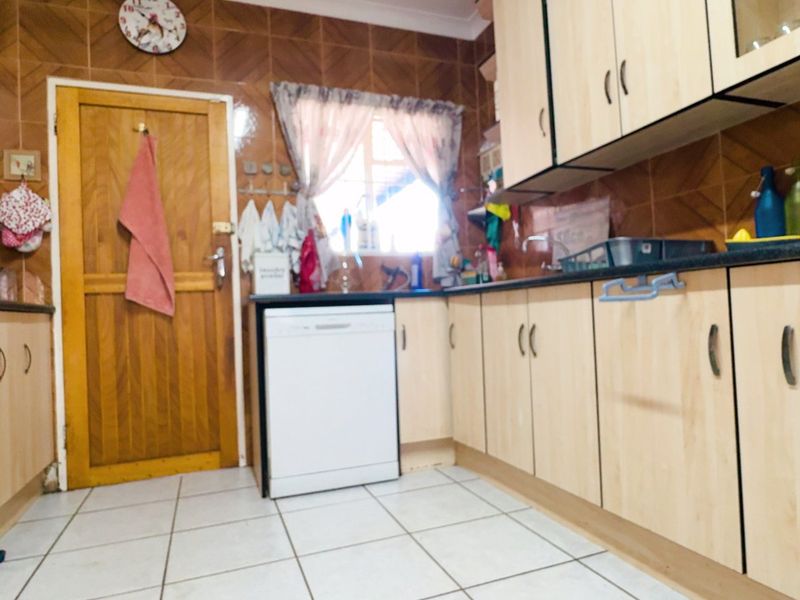 A functional kitchen featuring laminate cabinetry, tiled backsplash, and tiled flooring, equipped with a built-in oven and dishwasher.