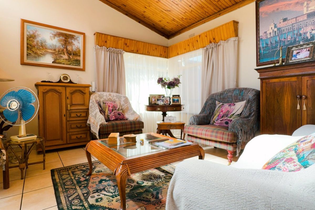 A cozy living room featuring a vaulted timber-clad ceiling, ceramic tiled flooring, and timber window pelmets, offering a warm and traditional aesthetic.