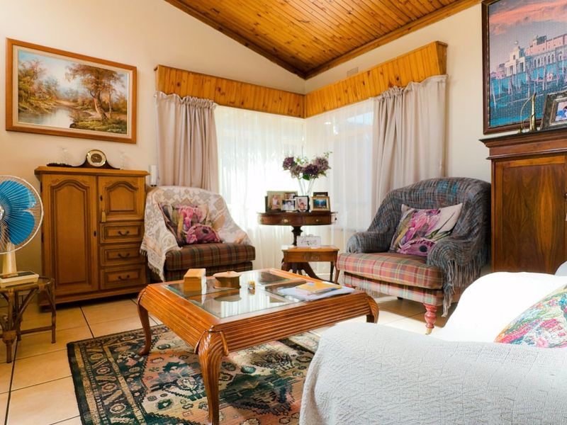 A cozy living room featuring a vaulted timber-clad ceiling, ceramic tiled flooring, and timber window pelmets, offering a warm and traditional aesthetic.