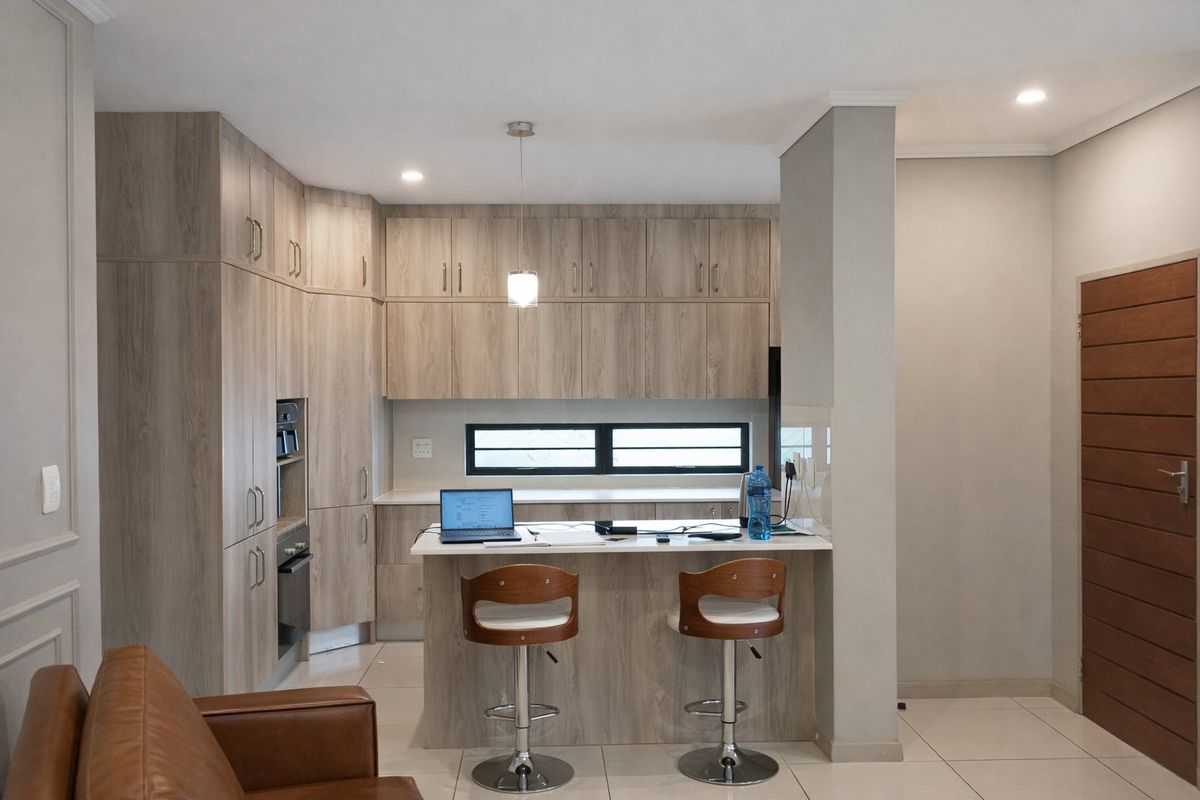 Modern kitchen featuring light wood-grain cabinetry, built-in oven and microwave, a functional island, and sleek tiled flooring in an open-plan layout.
