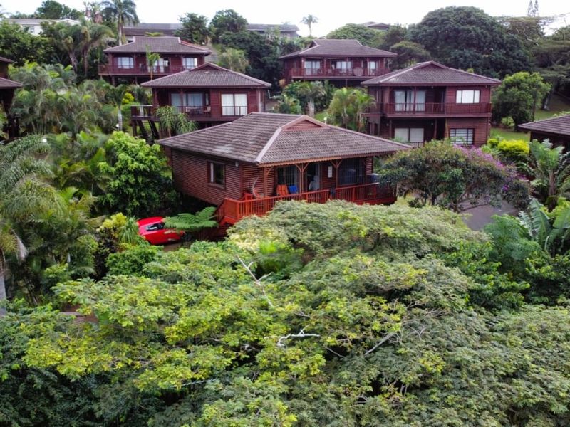 Aerial view of a residential complex featuring timber-clad townhouse units nestled within a lush, mature garden setting.