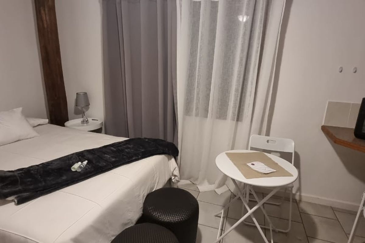 A compact bedroom featuring tiled flooring and a built-in shelf area, suitable for a small living space or studio setup.