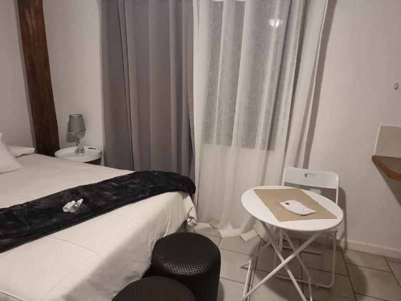 A compact bedroom featuring tiled flooring and a built-in shelf area, suitable for a small living space or studio setup.