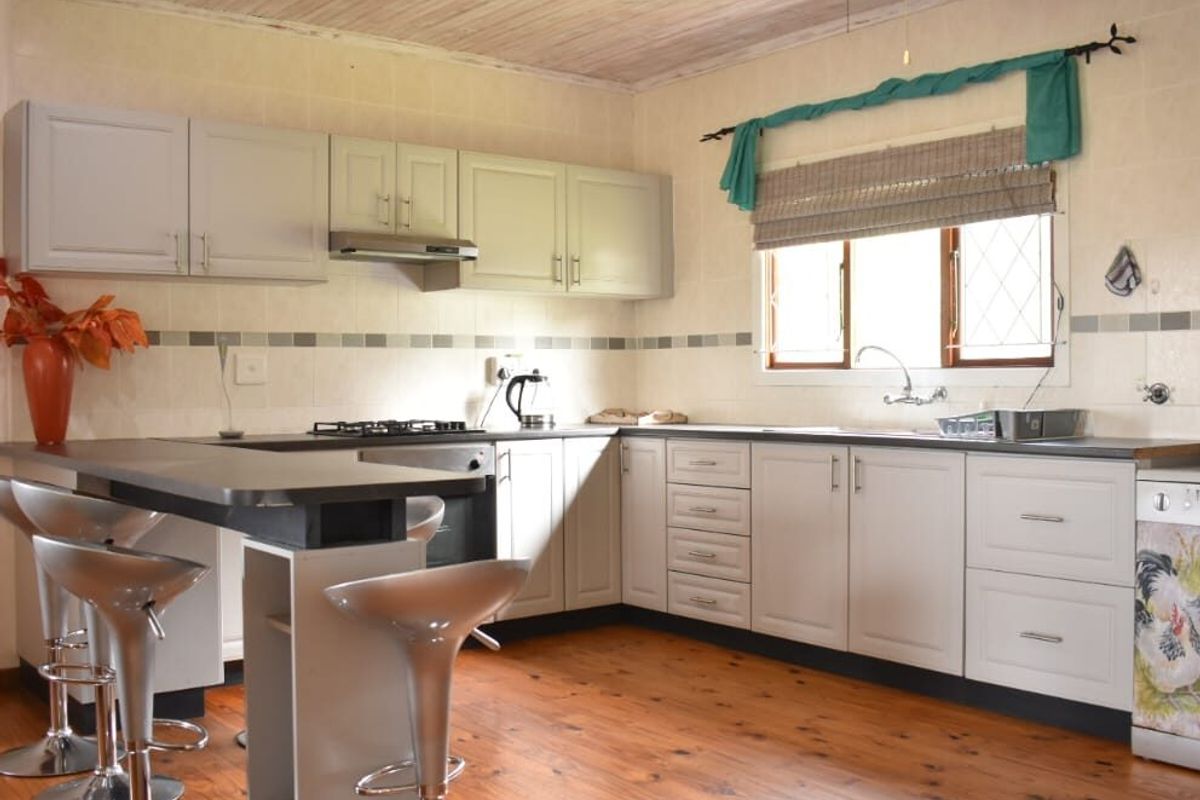 A functional kitchen featuring built-in cabinetry, gas hob, under-counter oven, and timber flooring, offering a classic layout with ample counter space.