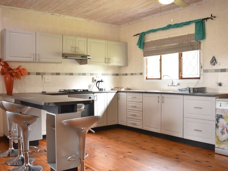 A functional kitchen featuring built-in cabinetry, gas hob, under-counter oven, and timber flooring, offering a classic layout with ample counter space.