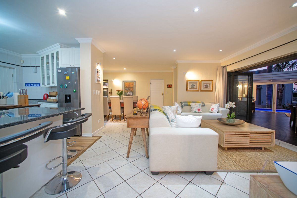 Spacious open-plan living area featuring a modern kitchen with granite countertops, tiled flooring, and seamless flow to an outdoor patio through bi-fold doors.