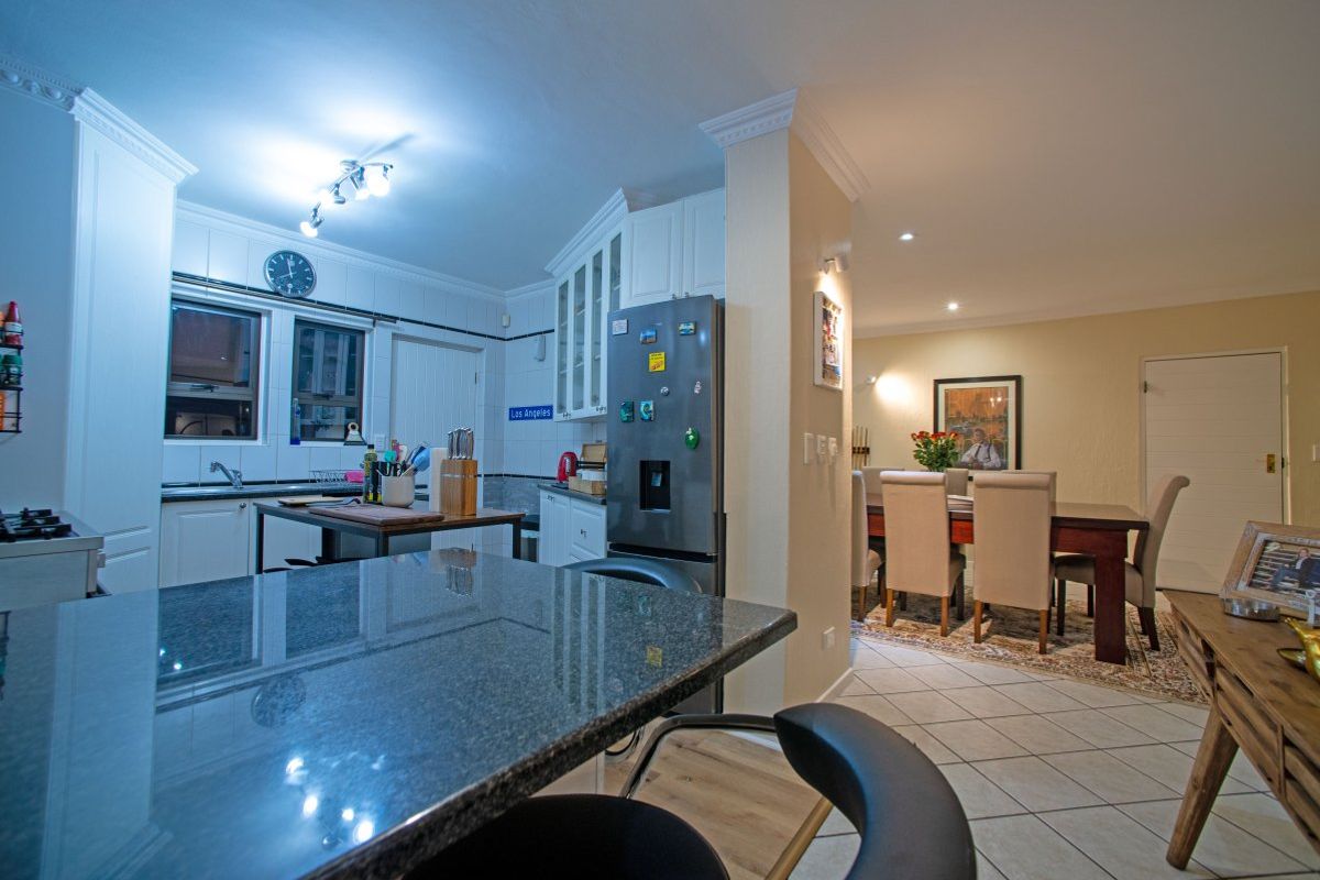 Open-plan kitchen and dining area featuring granite countertops, ample cabinetry, and tiled flooring, creating a functional and connected living space.