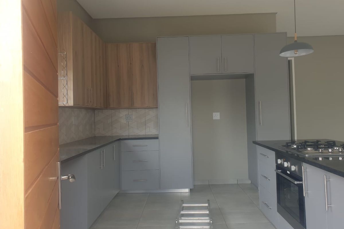 Modern kitchen featuring two-tone cabinetry, granite countertops, built-in oven, gas hob, and tiled flooring in a clean, contemporary layout.