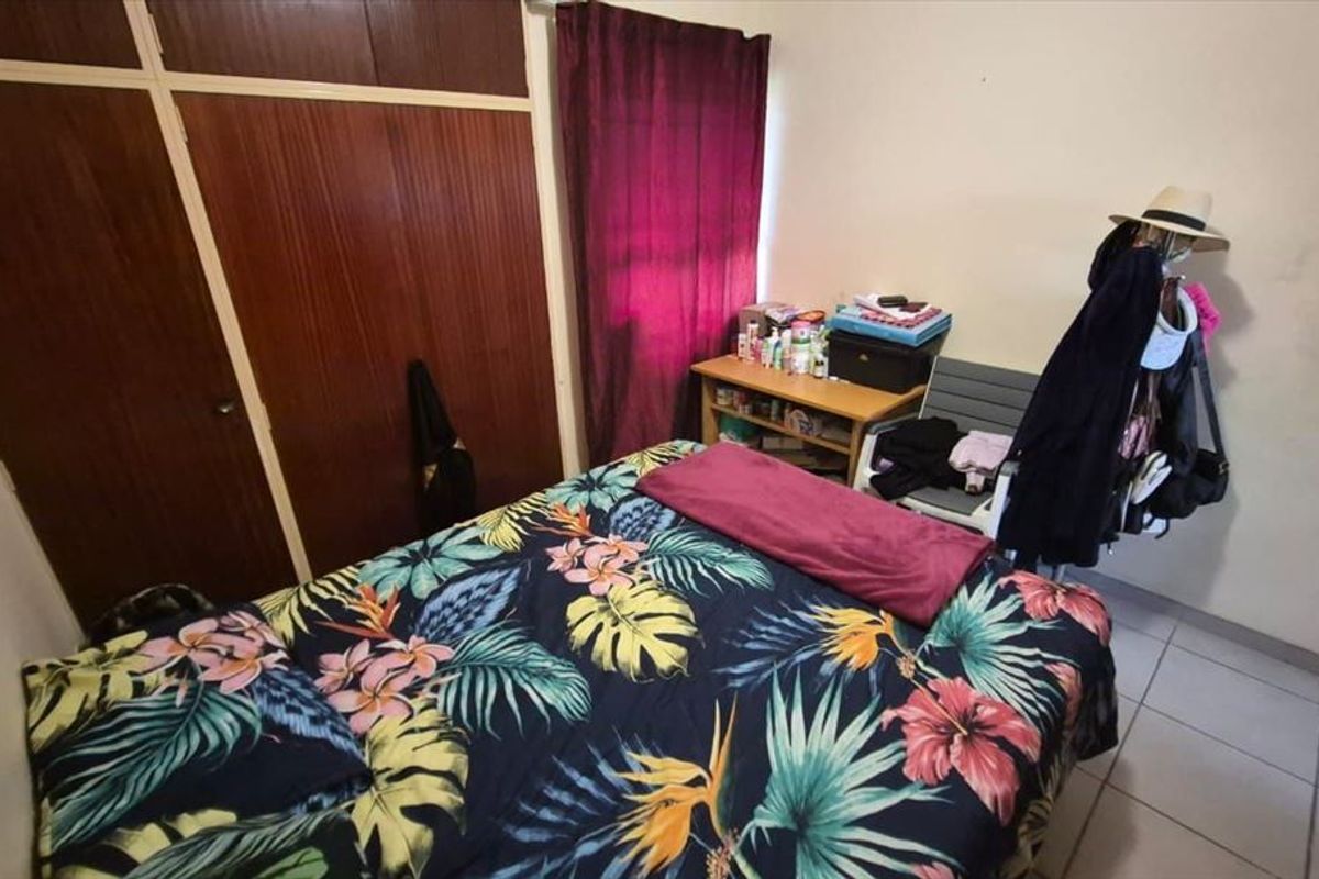 A bedroom featuring built-in wooden cupboards and tiled flooring, offering a functional space with potential for cosmetic updates.