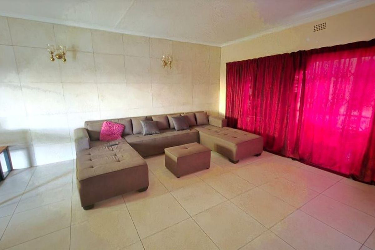 A spacious living room featuring large floor tiles and a textured feature wall, providing a neutral base for interior design.