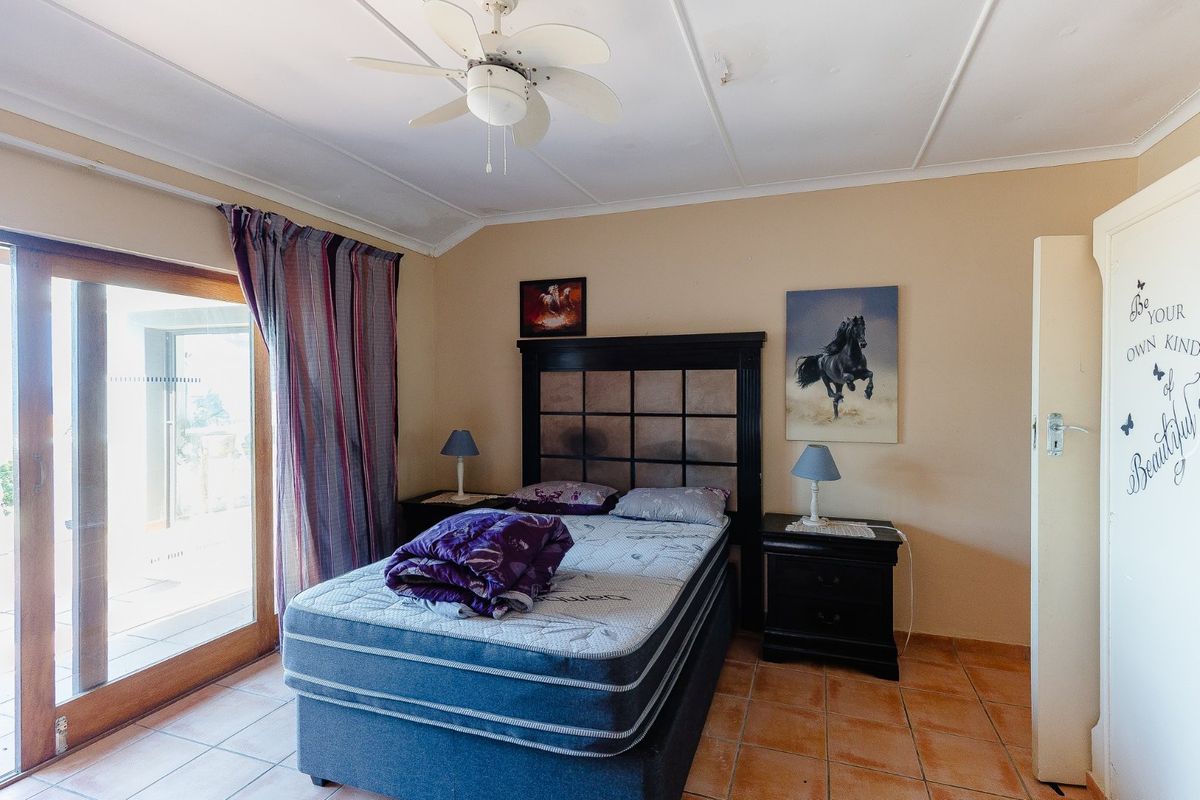 A bedroom featuring tiled flooring, a ceiling fan, and sliding glass doors providing direct access to the outdoor patio area.