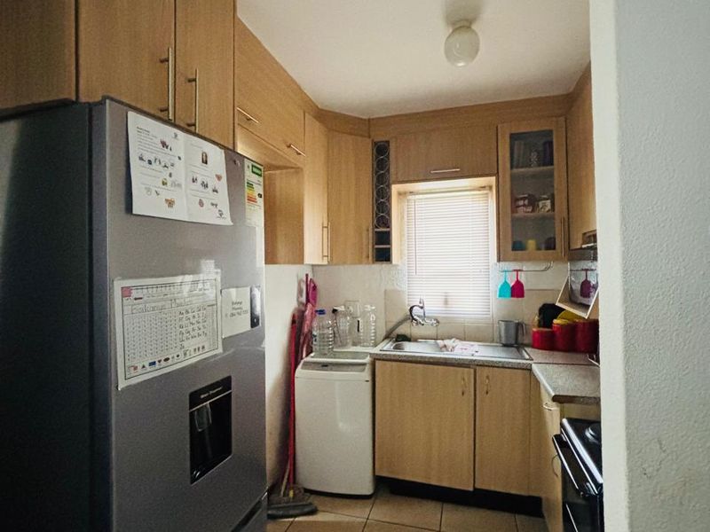 A compact kitchen featuring laminate cabinetry, tiled flooring, and a functional layout with integrated sink and oven space.