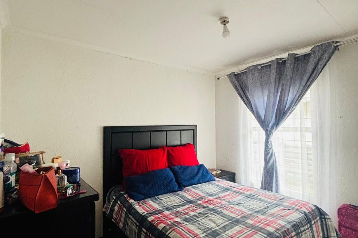 A functional bedroom featuring tiled flooring and a window with a curtain rod, providing a neutral base for personalization.