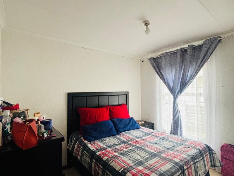 A functional bedroom featuring tiled flooring and a window with a curtain rod, providing a neutral base for personalization.