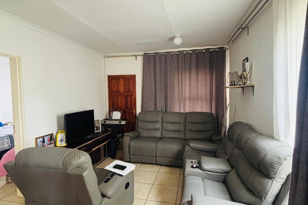 A functional living room featuring neutral tiled flooring and curtain rails, providing a blank canvas for potential interior updates.